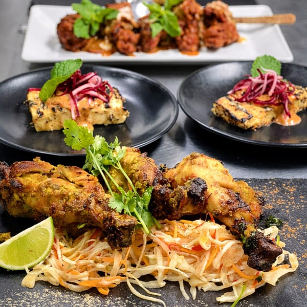 Indian dishes including grilled chicken drumsticks with slaw and lime, and paneer with pickled onions.